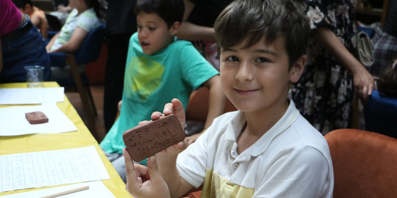 Çocuklar kile çivi yazısı ile isimlerini yazdı