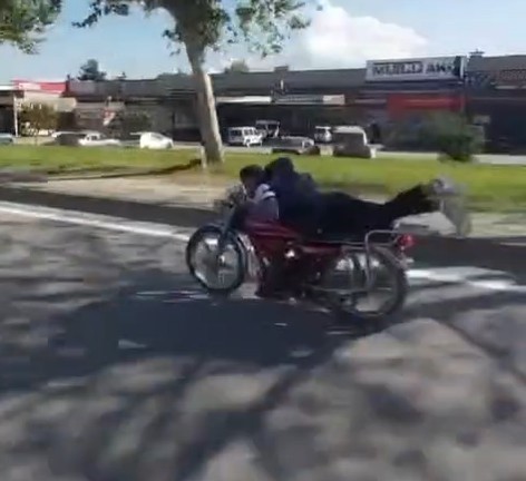 Plakasız motosiklet sürücüsü ellerini bırakıp motorun üzerine yatarak ilerledi